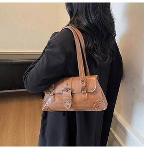 Detail view of brown vintage leather shoulder bag with metallic buckle and stud accents