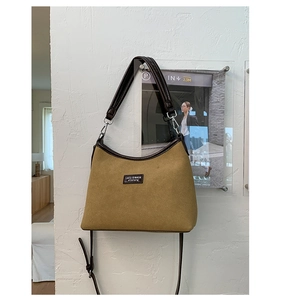 Detail of mustard yellow suede shoulder bag with brown leather trim and branding logo