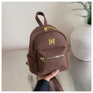 Detail showing vintage brown mini backpack with golden metal logo and matte texture surface