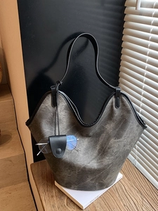 Large gray bucket tote bag with black trim and eyeglass holder in a stylish indoor setting