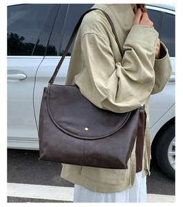 Détail d'un sac cabas vintage en cuir marron foncé avec boucle métallique dorée