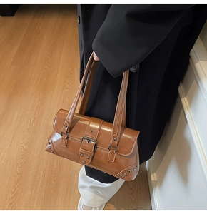 Close-up of vintage brown leather shoulder bag with metallic buckle and stud details