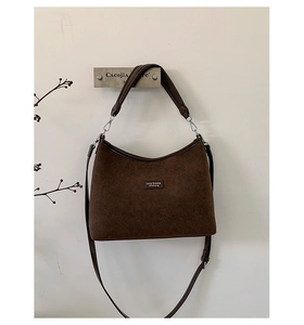 Detail view of coffee suede shoulder bag showing matte texture and branding label