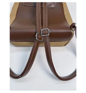 Dettaglio degli spallacci in pelle marrone con fibbie di regolazione in metallo sul zaino