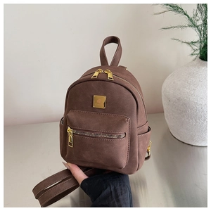 Macro shot of brown faux leather texture and gold logo buckle on the mini backpack