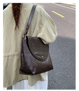 Détail d'un sac cabas marron vintage avec grand rabat et boucle en métal doré