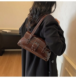 Detail of vintage dark brown leather underarm bag with silver rivets and buckle
