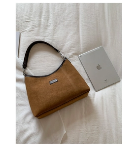 Top view of brown suede hobo bag next to iPad showing textured leather and size scale