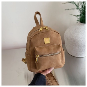 Close-up of a mini brown suede backpack with gold zippers and a front pocket