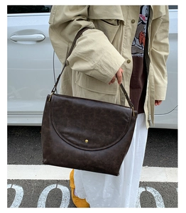 Détail du sac cabas marron vintage avec boucle dorée sur mannequin en trench