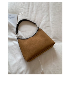 Detailed top view of brown suede underarm bag with zipper on a white textured background
