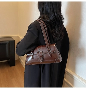 Detail of vintage dark brown glossy leather shoulder bag with metallic stud accents