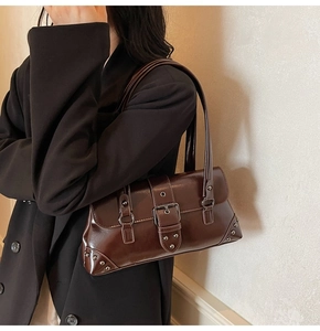 Detailed close-up of dark brown vintage faux leather shoulder bag with silver buckle and studs