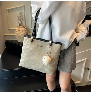 Detail of taupe marble-textured tote bag featuring a cute white sheep charm and black straps