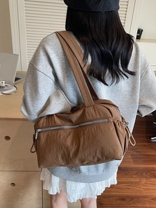 Brown nylon tote bag with multiple pockets and drawstring detail in minimalist style