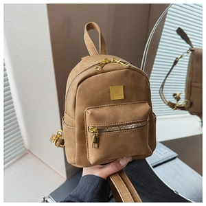 Close-up of brown matte leather backpack featuring a golden square logo metal plate detail