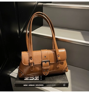 Detail of vintage caramel brown leather shoulder bag with buckle and rivet accents