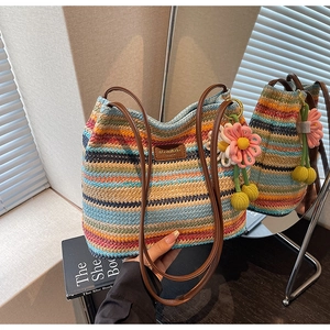Detail der gestreiften Strick-Beuteltasche mit Ledergriffen und einem bunten Blumenanhänger