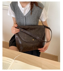 Détail du sac bandoulière vintage en cuir huilé marron avec rivets en laiton décoratifs
