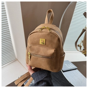 Close-up of a vintage tan suede mini backpack with gold zippers and metal logo plate