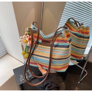 Detail der bunt gestreiften gewebten Tasche mit braunen Lederriemen und Blumenanhänger