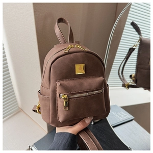 Close-up of brown mini backpack with golden metal zippers and front logo plate detail