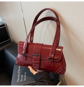 Detail view of the vintage dark red patent leather handbag with metal buckle and rivets