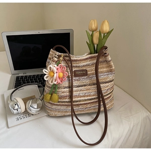 Detail der gewebten Streifen-Tasche mit Leder-Logo und floralem Anhänger-Accessoire
