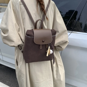 Dettaglio dello zaino vintage marrone opaco con patta in pelle e ciondolo da baseball