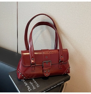 Detail of burgundy glossy leather bag with silver rivets and metal buckle design