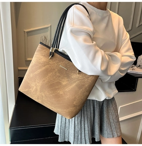 Close-up of a large vintage brown tote bag with black trim and gold metal bar detail