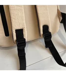 Dettaglio degli spallacci regolabili in tessuto nero e fibbia su zaino in tela beige