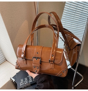 Detail view of retro brown shoulder bag with metal buckle and silver studs on corners