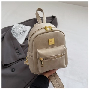 Detail of beige faux leather mini backpack with golden logo plaque and double zipper pockets