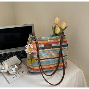 Nahaufnahme der gestreiften gewebten Beuteltasche mit Lederriemen und Blumenanhängern