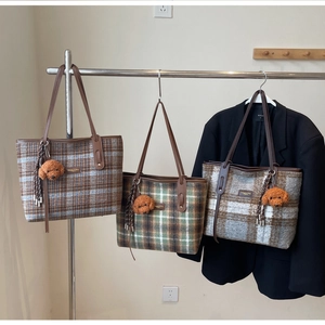 Trois grands sacs cabas en laine à carreaux avec breloques ourson sur des cintres