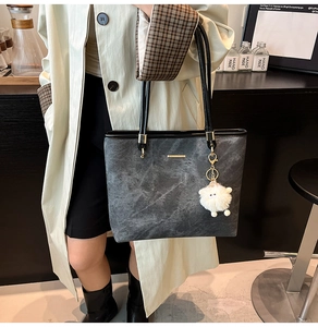Detail of grey marble pattern tote bag with gold metal trim and white sheep plush charm