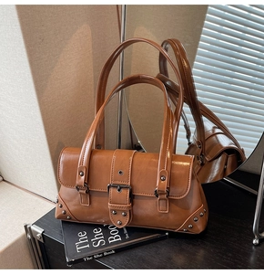 Detail of vintage brown glossy leather shoulder bag with metal buckles and rivets