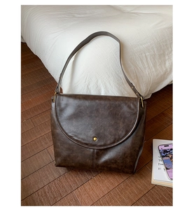 Détail d'un sac à main vintage marron foncé avec boucle dorée sur un parquet en bois