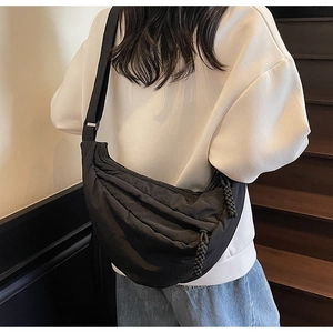 Dettaglio della borsa a mezzaluna in nylon nero con tracolla larga regolabile e cerniera