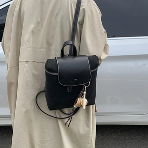 Dettaglio di zaino vintage in tela nera con patta in pelle e cuciture a contrasto
