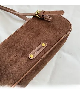 Detalle de bolso de hombro en ante marrón con remaches dorados y hebilla ajustable