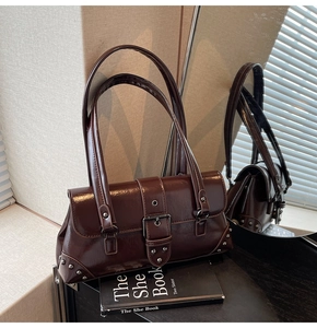 Detail of dark brown glossy leather shoulder bag with vintage buckles and metal rivets