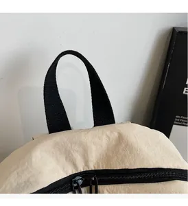 Dettaglio dello zaino beige con manici neri in fettuccia e doppia zip scorrevole