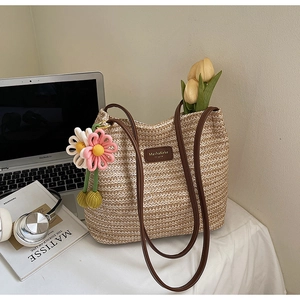 Detail der handgewebten beigen Beuteltasche mit braunem Lederlogo und Blumenanhänger