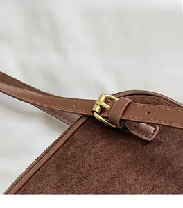 Primer plano detallado de la hebilla de metal dorado y el ante marrón del bolso retro