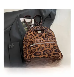 Détails d'un sac à dos en velours léopard avec nœud décoratif et pendentif en cœur