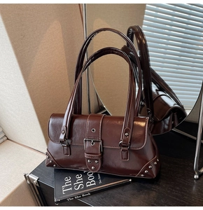 Detailed close-up of a vintage dark brown shoulder bag with shiny faux leather and silver rivets