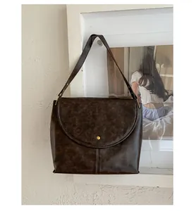 Détail du sac à bandoulière marron vintage avec un bouton pression en métal doré chic
