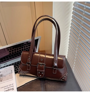 Detail of dark brown oil-wax leather shoulder bag with vintage metal buckle and studs